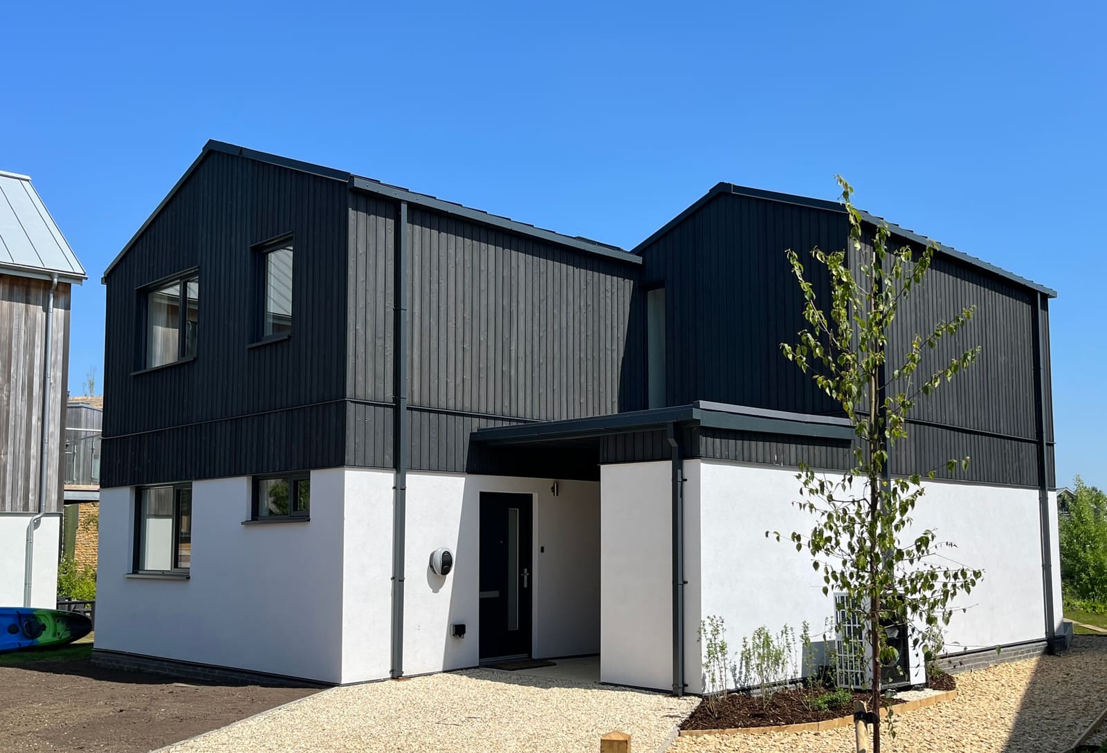 Cotswolds home with black timber cladding over white render