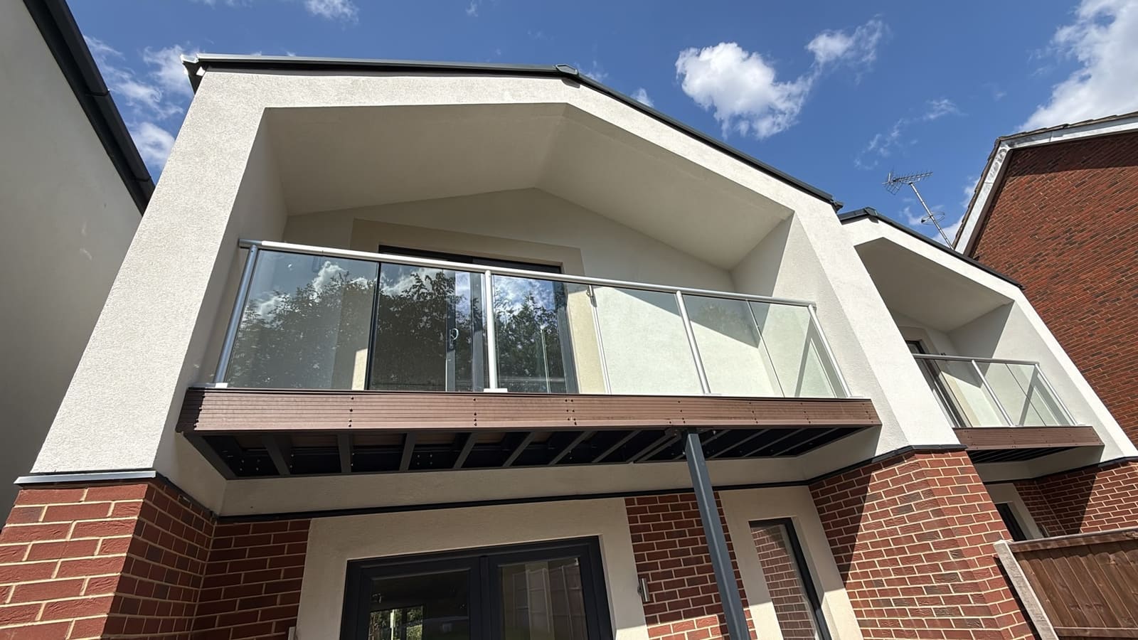 Glass balcony set into a rendered gable